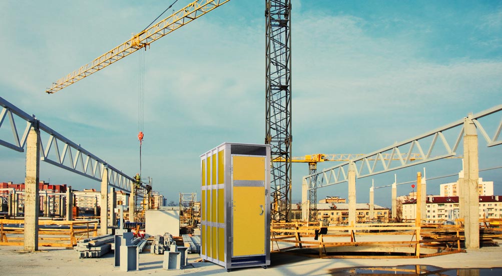 Skycrapper Portable Restroom | Yellow Colored Skycrapper Portable Toilet Outdoors at a Construction Site with a Crane in the Background